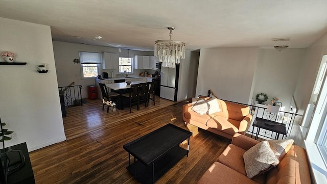 living area with baseboards, visible vents, a chandelier, and wood finished floors