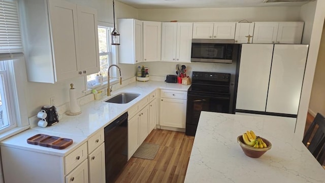 kitchen with black appliances, light stone counters, a sink, and white cabinets