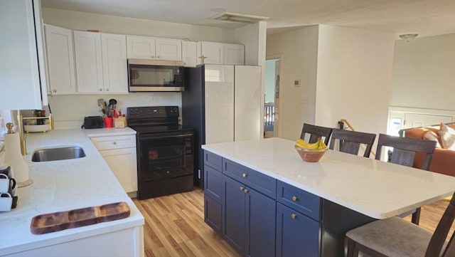 kitchen with light wood-style flooring, a breakfast bar, white cabinetry, black electric range oven, and stainless steel microwave