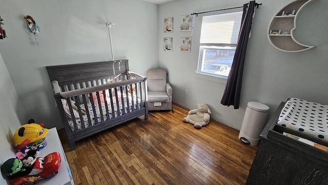 bedroom with a crib and wood-type flooring