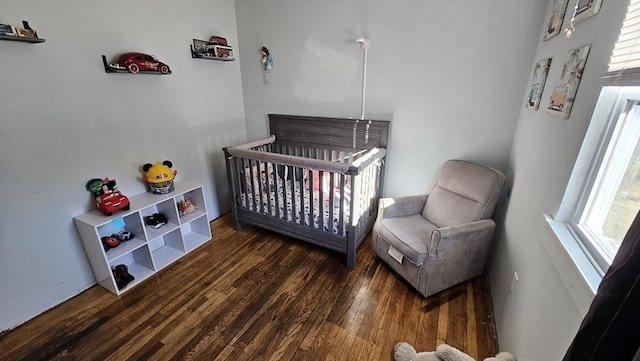 bedroom featuring a nursery area, multiple windows, and wood finished floors