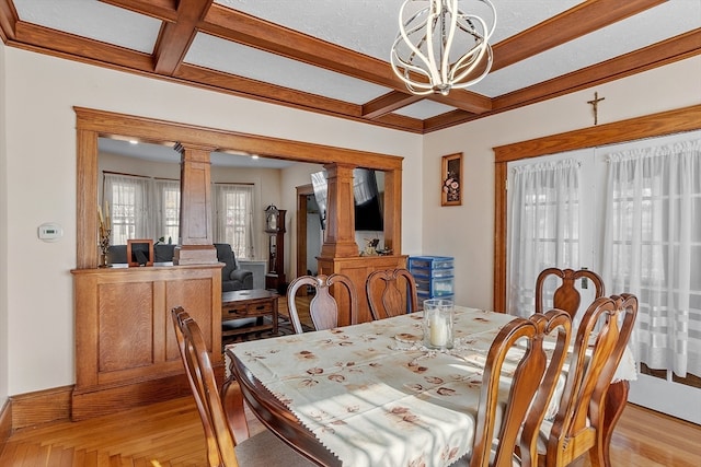 dining area with ornate columns, coffered ceiling, an inviting chandelier, beamed ceiling, and light hardwood / wood-style flooring