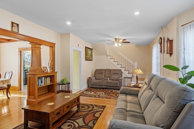 living room with ceiling fan, light wood-type flooring, and decorative columns