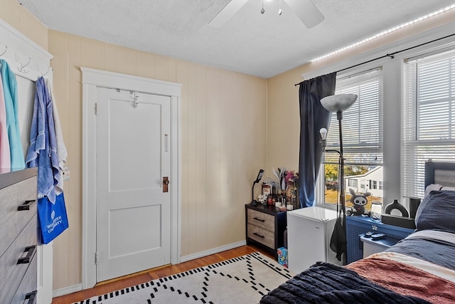 bedroom with ceiling fan, a textured ceiling, and light wood-type flooring