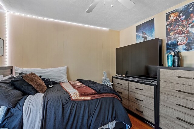 bedroom featuring ceiling fan, dark hardwood / wood-style floors, and a textured ceiling