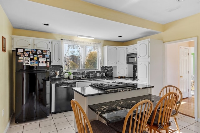 kitchen with sink, black appliances, light tile patterned floors, backsplash, and white cabinets