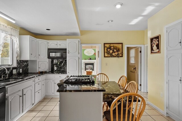 kitchen featuring stainless steel appliances, white cabinetry, sink, backsplash, and a kitchen island