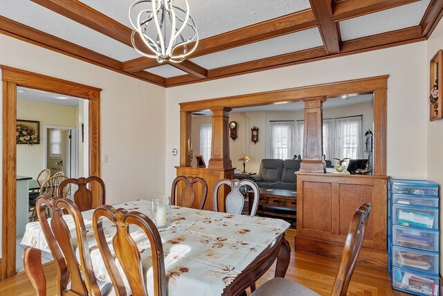 dining area with decorative columns, a notable chandelier, and light hardwood / wood-style flooring