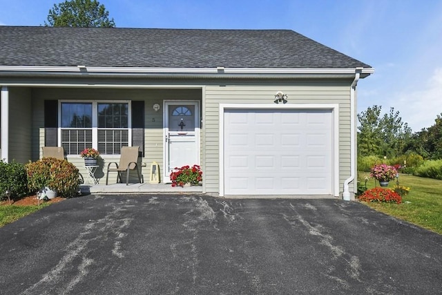 single story home featuring a garage, covered porch, aphalt driveway, and roof with shingles