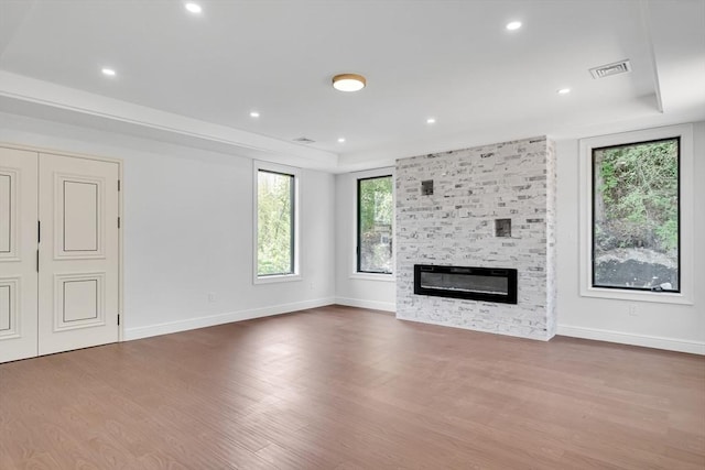 unfurnished living room with a raised ceiling, a fireplace, and hardwood / wood-style flooring