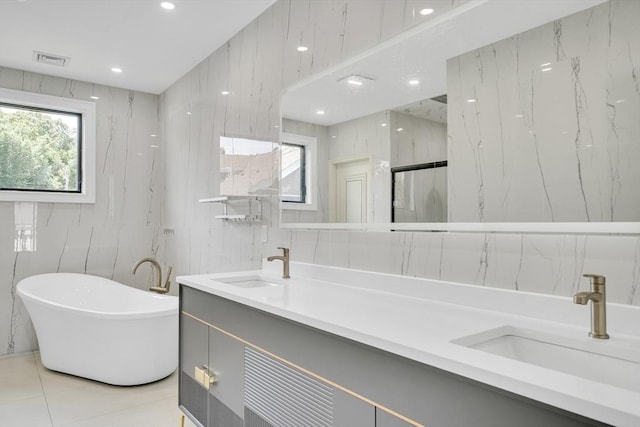 bathroom with tile patterned flooring, vanity, independent shower and bath, and tile walls