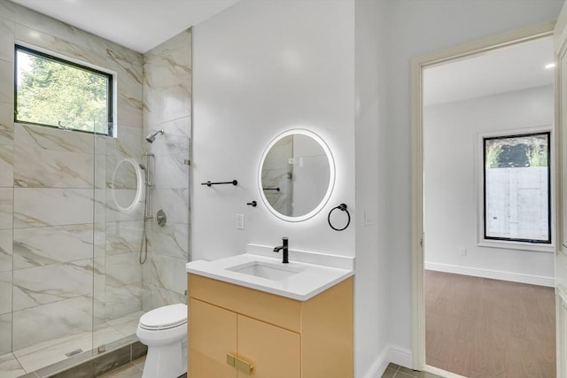 bathroom with a tile shower, vanity, hardwood / wood-style flooring, and toilet