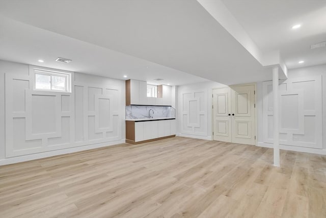 basement with sink and light hardwood / wood-style floors