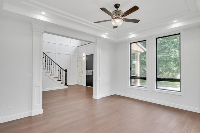 interior space with a raised ceiling, plenty of natural light, ceiling fan, and wood-type flooring