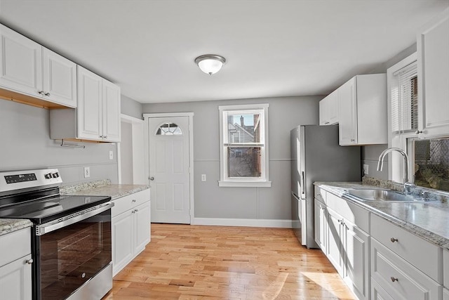 kitchen featuring light wood-style flooring, white cabinets, stainless steel appliances, and a sink