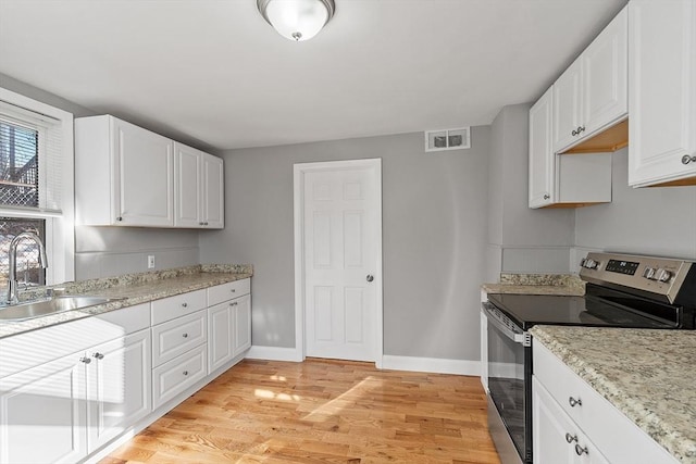 kitchen featuring visible vents, light wood-style flooring, stainless steel electric range, a sink, and white cabinets