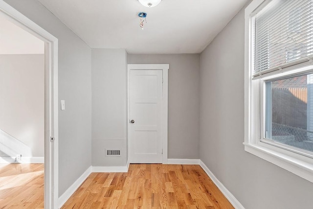 unfurnished room featuring plenty of natural light, baseboards, visible vents, and light wood finished floors