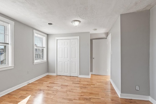 unfurnished bedroom featuring a closet, baseboards, visible vents, and light wood finished floors