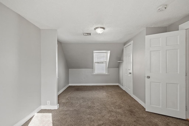 bonus room with baseboards, visible vents, carpet floors, vaulted ceiling, and a textured ceiling