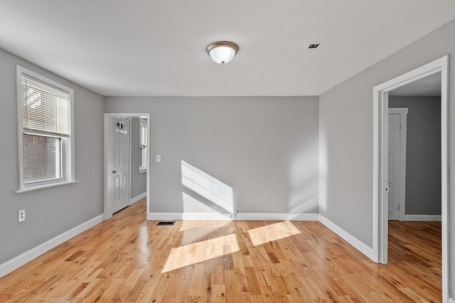 empty room with visible vents, light wood-style floors, and baseboards