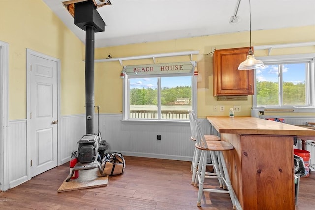 49 Boathouse Rd, Groton, MA 01450 - kitchen featuring a wood stove, wainscoting, wood finished floors, a kitchen breakfast bar, and brown cabinets
