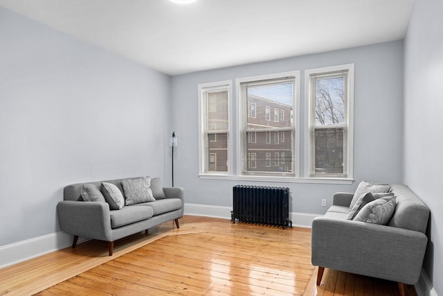 sitting room featuring radiator, light wood-style floors, and baseboards