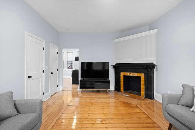 living area with a fireplace, light wood finished floors, and baseboards