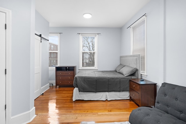 bedroom featuring a barn door and light wood-type flooring