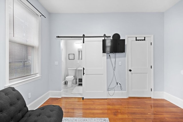 sitting room featuring baseboards, light wood-style flooring, and a barn door