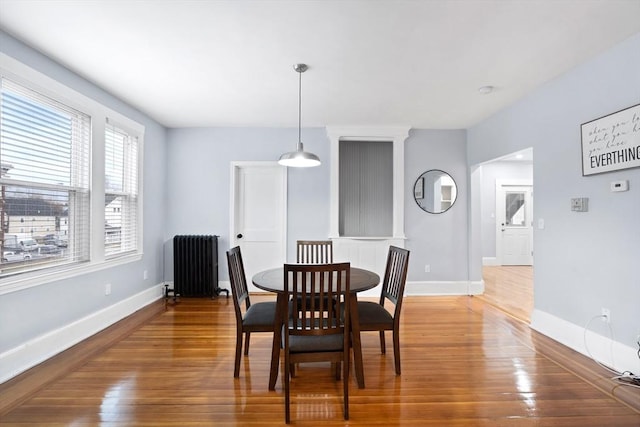 dining room with radiator heating unit, wood finished floors, and baseboards