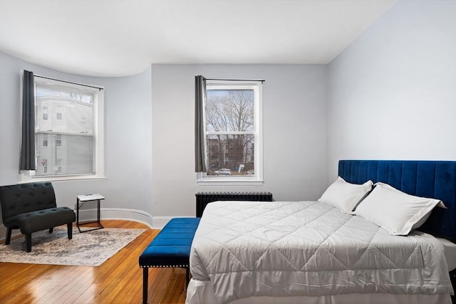 bedroom featuring radiator, wood-type flooring, and baseboards