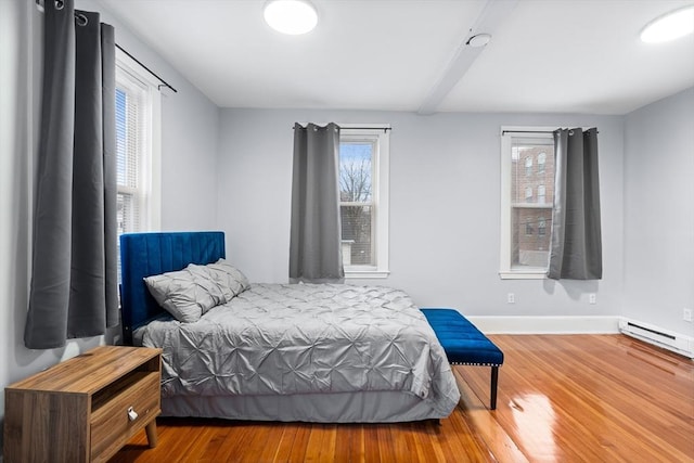 bedroom with wood finished floors, multiple windows, and baseboards