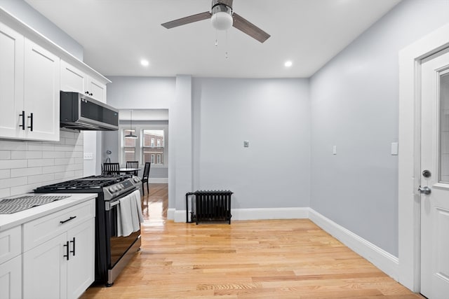 kitchen with light wood-type flooring, backsplash, white cabinetry, ceiling fan, and stainless steel appliances