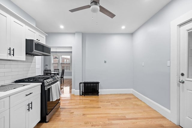 kitchen with stainless steel appliances, a ceiling fan, decorative backsplash, radiator, and light countertops