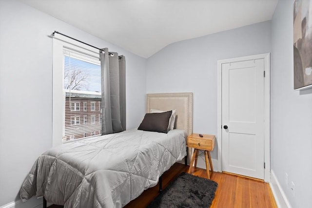 bedroom featuring vaulted ceiling, wood finished floors, and baseboards
