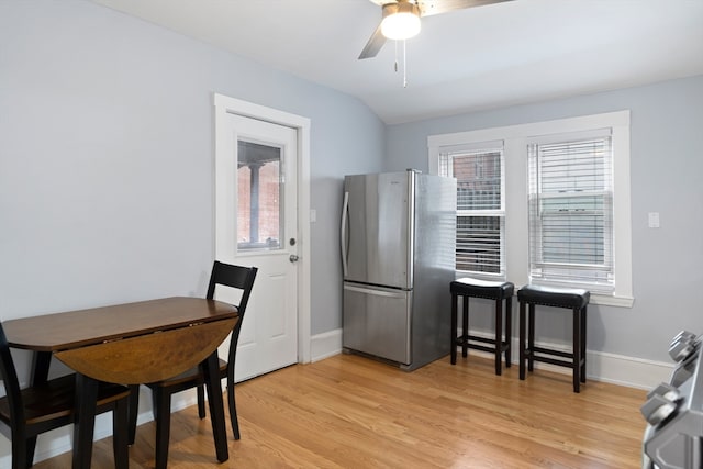 dining space with ceiling fan, light wood-type flooring, and vaulted ceiling