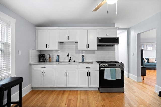 kitchen with gas stove, stainless steel microwave, a sink, tasteful backsplash, and light countertops