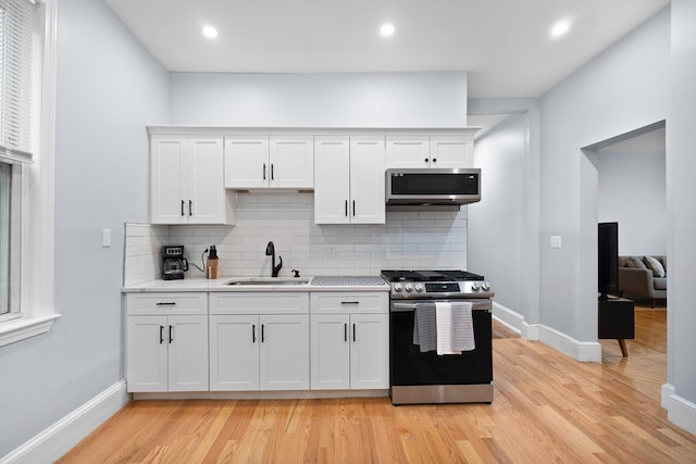 kitchen featuring white cabinetry, stainless steel appliances, sink, and light wood-type flooring