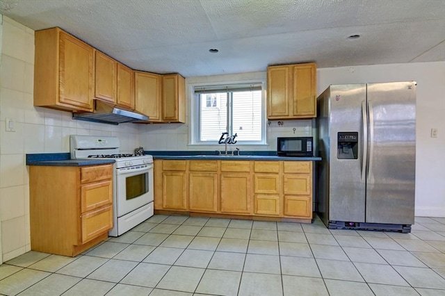 kitchen with stainless steel fridge with ice dispenser, under cabinet range hood, a sink, white range with gas stovetop, and black microwave