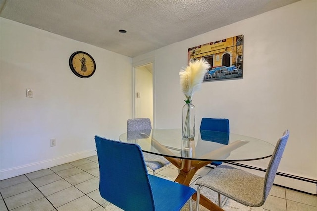 dining area with light tile patterned flooring, a textured ceiling, and baseboards