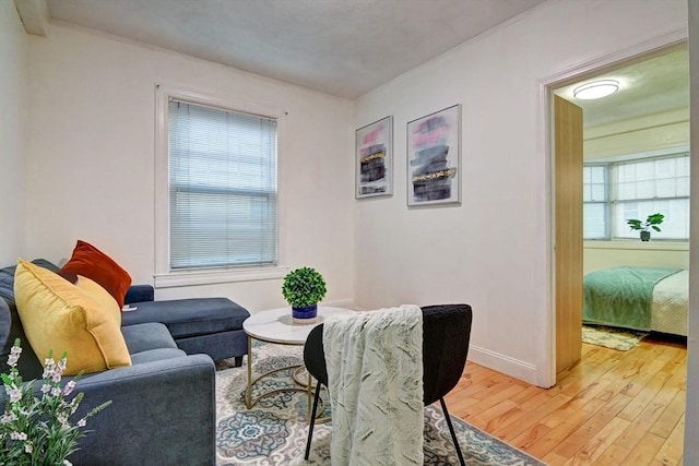 living room featuring baseboards, ornamental molding, and light wood finished floors