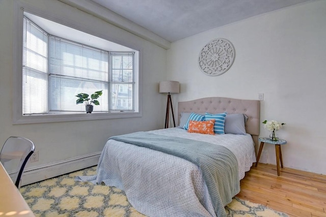 bedroom featuring a baseboard heating unit and wood finished floors