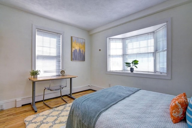 bedroom featuring baseboard heating and wood finished floors