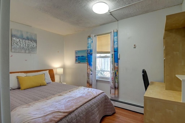 bedroom featuring baseboard heating and wood finished floors