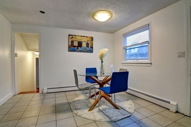 tiled dining space with a textured ceiling, baseboard heating, and baseboards