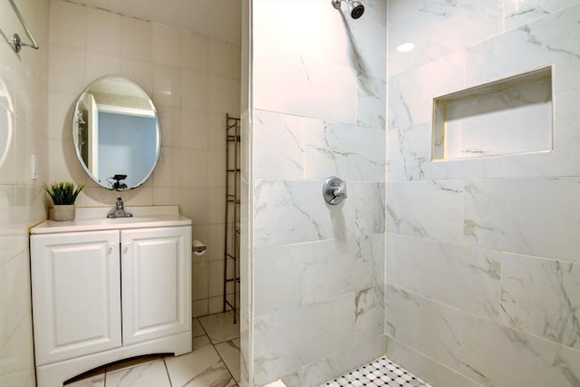 bathroom with tile walls, a tile shower, and vanity