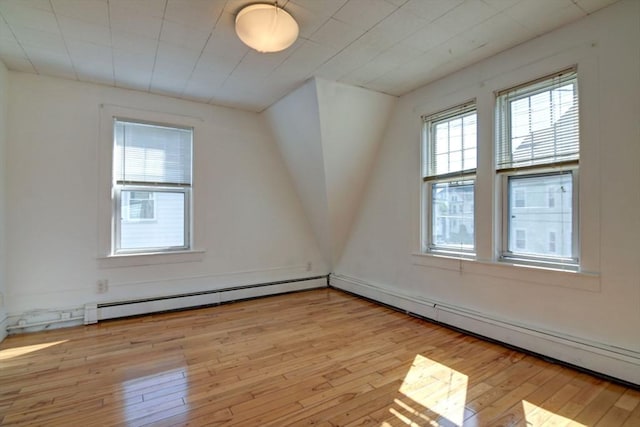 bonus room with a baseboard heating unit and light wood-style flooring