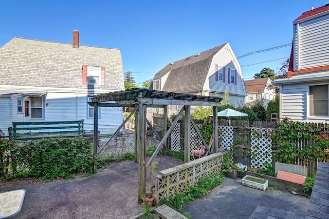 exterior space with a pergola, a gambrel roof, a shingled roof, and fence
