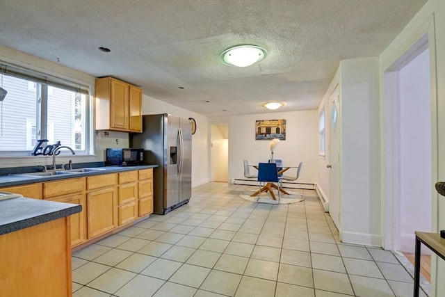 kitchen with dark countertops, a textured ceiling, a sink, and stainless steel fridge with ice dispenser