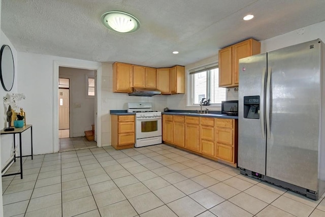 kitchen featuring under cabinet range hood, white gas range, black microwave, stainless steel refrigerator with ice dispenser, and dark countertops